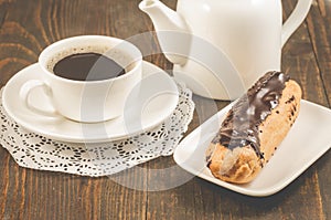 Coffee cup, teapot and eclairs on a wooden background/breakfast