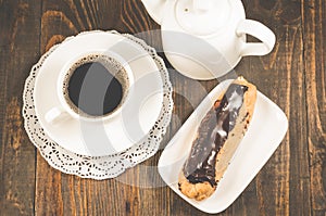 Coffee cup, teapot and eclairs on a wooden background/breakfast