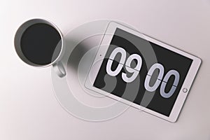 Coffee cup with time display on digital clock on tablet computer