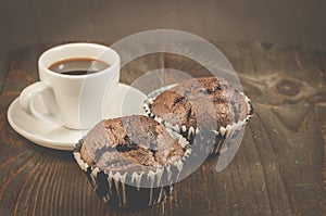 coffee cup and a two chocolate muffin/coffee cup and a two chocolate muffin on a wooden table, selective focus