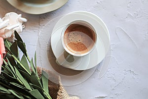 Coffee cup with vintage white and pink rose flower in vase on table.