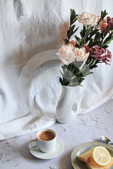 Coffee cup with vintage white and pink rose flower in vase on table.