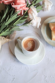 Coffee cup with vintage white and pink rose flower in vase on table.