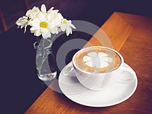Coffee cup with White daisy flowers decoration on wooden table