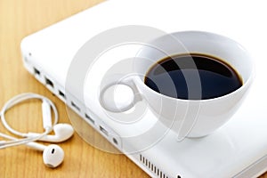 Coffee cup on white laptop and earphone, relax time and business photo