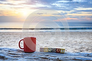 Coffee cup on wood log at sunset or sunrise beach