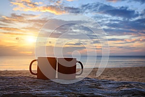 Coffee cup on wood log at sunset or sunrise beach