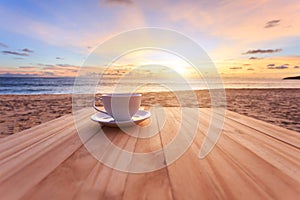 Coffee cup on wood table at sunset or sunrise beach