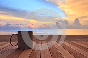 Coffee cup on wood table at sunset or sunrise beach