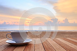 Coffee cup on wood table at sunset or sunrise beach