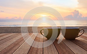 Coffee cup on wood table at sunset or sunrise beach