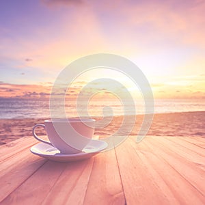 Coffee cup on wood table at sunset or sunrise beach with lens fl