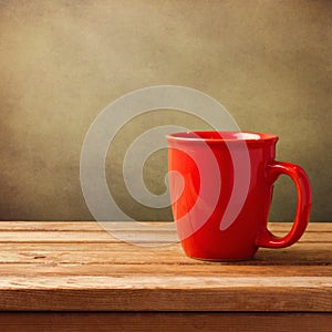 Coffee cup on wooden table over grunge background