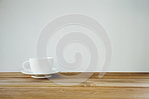 Coffee cup on wooden table over white background. Vintage tone