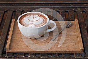 Coffee in a cup on a wooden tray with coffee art