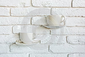 Coffee cups as lamp decorations on a white brick wall in modern loft cafe