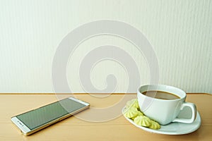 Coffee in cups with candy and white phones.