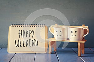 coffee cups next to notebook with phrase happy weekend