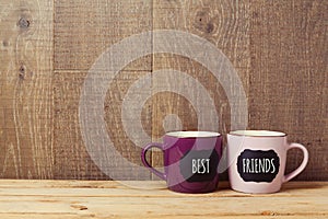 Coffee cups on wooden table with chalkboard sign and best friends text. Friendship day celebration