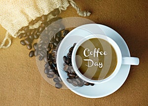 Coffee Day inscription written on the hot coffee with coffee beans background.