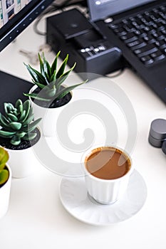 Coffee on the desk along a keyboard and some flowers