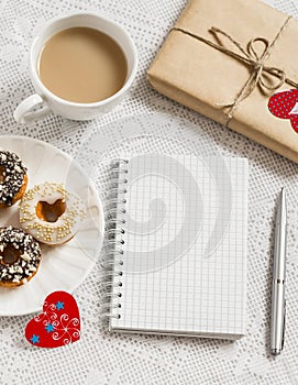 Coffee, donuts, homemade Valentine's day gift , red paper hearts, blank open notebook