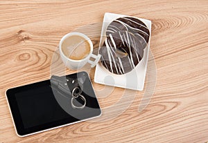 Coffee, donuts and tablet on wooden background