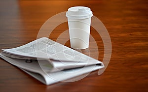 Coffee drink in paper cup and newspaper on table