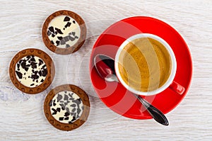 Coffee espresso in cup, spoon on saucer, cookies with cream and chocolate on table. Top view