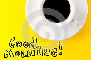 Coffee espresso in small white ceramic cup on yellow vibrant background. Text Good Morning. Minimalism Food Morning Energy