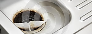 Coffee filter paper draining in kitchen sink plughole