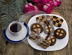 Coffee, fir-tree branch, roses and a plate with baking