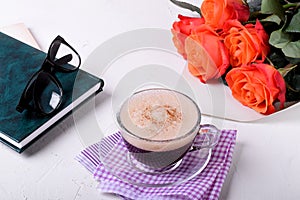 Coffee with foam and cinnamon, book, glasses and roses