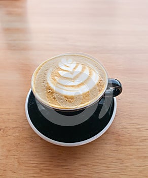 Coffee froth art in black cup and saucer photo