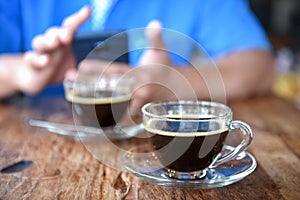 Coffee glass on wooden table with blurred background people play