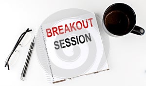 Coffee,glasses,pen and notebook written with Breakout Sessions on white background