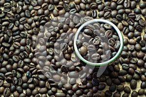 Coffee grain in a decorative cup. top view. roasted coffee beans around.