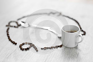 Coffee grains folded in the form of a clock on a wooden background. Instead of the number 7, a cup of coffee, which means it`s