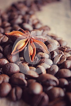 coffee grains and star anise on a wooden table, brown abstract background, warm texture, macro