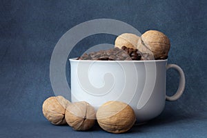 Coffee grains in a white cup and nuts