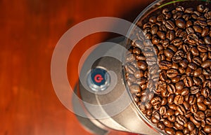 Coffee grinder with red start button, filled with fresh coffee beans and copy space in background for text, abstract, details