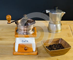 Coffee grinder and roasted coffee beans from the side in a wooden dish