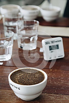 Coffee grounds with hot water in the ceramic cup on the table is preparing for professional Q Grader to testing and inspecting the