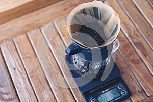 Coffee grounds in paper filter on digital coffee scale while making a drip coffee