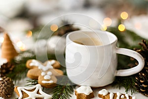 Coffee, homemade gingerbread cookies, pine cones decorations and warm lights on white  table