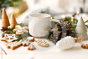 Coffee, homemade gingerbread cookies, pine cones decorations and warm lights on white  table