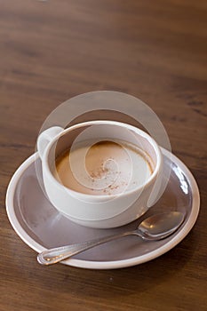 Coffee i n a cup on a wooden table with a spoon