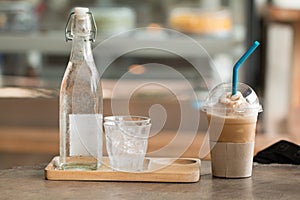 Coffee with ice capucino frape cup drink on wooden desk with blurred coffee shop photo