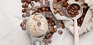 Coffee ice cream ball in a scoop and roasted coffee beans on white clay background.