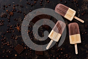 Coffee ice cream on a stick on a dark brown background. Double ice cream. Top view, copy space. Summer concept